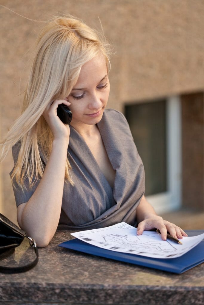 Beautiful woman sitting, calling to phone and reading documents